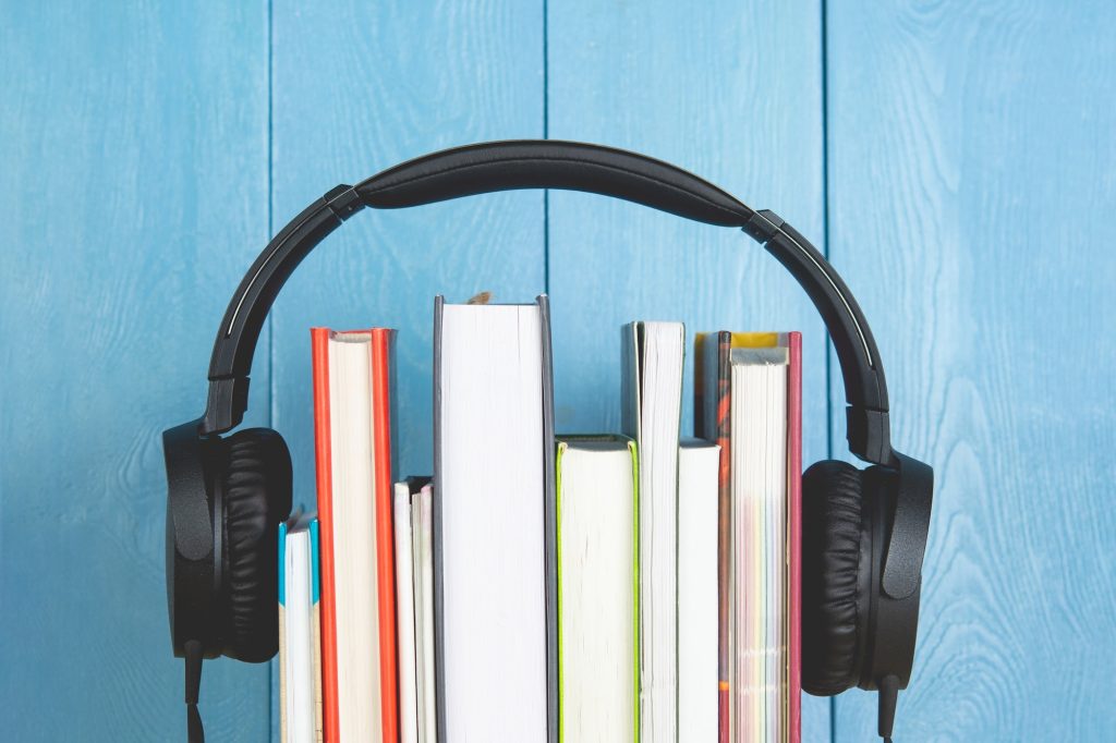 headphone and books on blue background. audio book